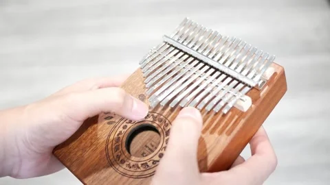 Pair of hands playing a tune with a Kalimba instrument Видео 246580234
