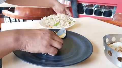 Pair of hands taking chowmein from a white plate to a black plate at a Stock Footage 128027635