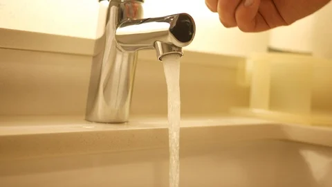 A pair of hands turn on running water in sink Stock Footage 113579047