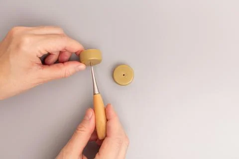 Pair of hands working with two round, beige plastic caps. create a hole in .. Stock Photos