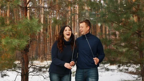 The pair is holding bengal flames. He go and smile. Shooting in motion. Snow Stock Footage 99923066