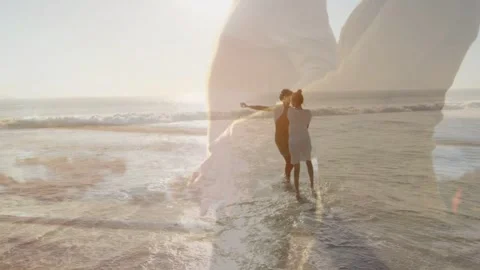 Pair holding, stepping in surf, twirling as pregnant-torso overlay shifting over Vídeo Stock 333063329