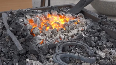 A pair of horseshoes cools in a forging brazier. Stock Footage 120572504