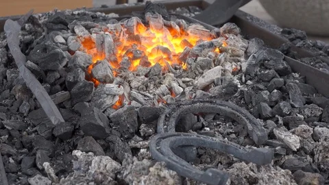 A pair of horseshoes cools in a forging brazier. Stock Footage 120572537