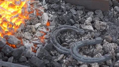 A pair of horseshoes cools in a forging brazier. Stock Footage 120572599
