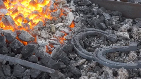 A pair of horseshoes cools in a forging brazier. Stock Footage 120572620
