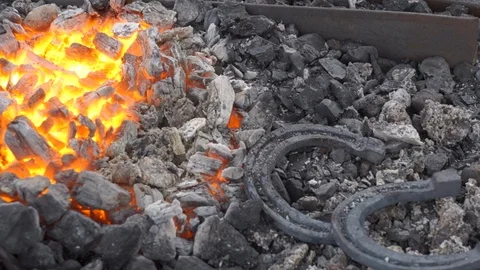 A pair of horseshoes cools in a forging brazier. Stock Footage 120572864