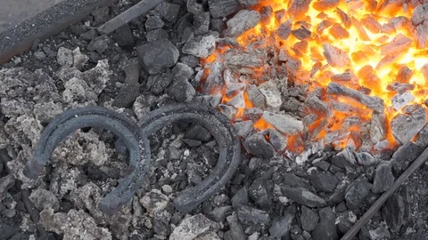 A pair of horseshoes cools in a forging brazier. Stock Footage 120573016
