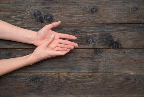 Pair of human hands with palms up placed on dark wooden surface, female han.. Stock Photos