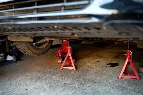 Pair of jack stands under the car during repair vehical. Safety oil changing. Stock Photos