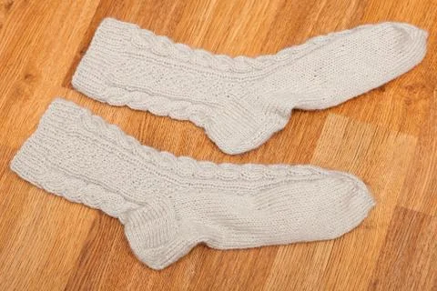 Pair of knitted woolen socks lying on the wooden floor Stock Photos