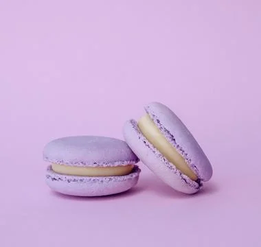 Pair of lavender macarons on solid lilac background, pastel dessert minimal.. Stock Photos