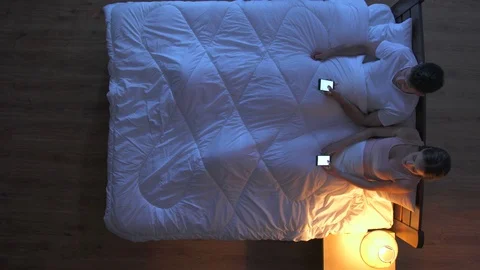 The pair lay phone in the bed. night time. view from above Stock-Footage 75552219