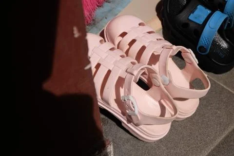 A pair of light pink, rubberized gladiator-style sandals placed on a grey t.. Stock Photos