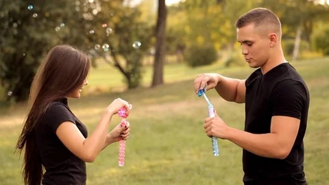 Pair of lovers blowing bubbles outdoors Stock Footage 77525541