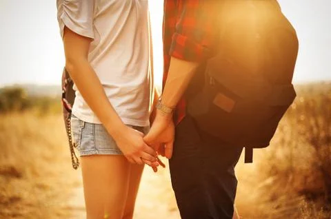 A pair of lovers hold hands in the rays of the setting sun Stock Photos