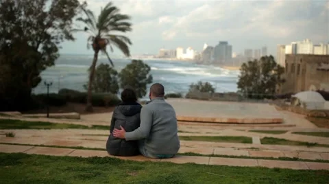 A pair of lovers sitting embracing, looking at the stormy sea or ocean views and Stock Footage 47414281