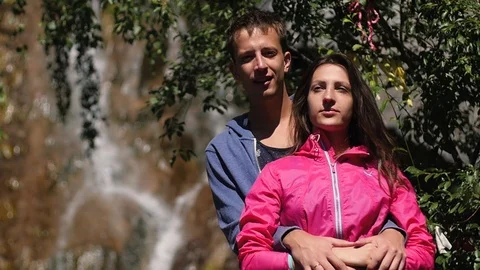 A pair of lovers stand against a waterfall. Honeymoon. kiss on the background of Vídeo Stock 106102105
