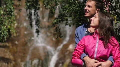 A pair of lovers stand against a waterfall. Honeymoon. kiss on the background of Stock-Footage 106102146
