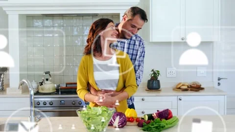 Pair making salad, man hugging woman, tech icons popping over couple, showing Vídeo Stock 333221013