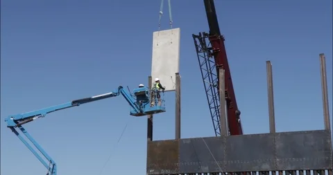 A pair of men inside a telehandler placing a concrete panel Stock Footage 99043279