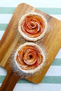 Pair of Mini Rose Shaped Apple Tartlets Sprinkled with Powdered Sugar Fotos de archivo