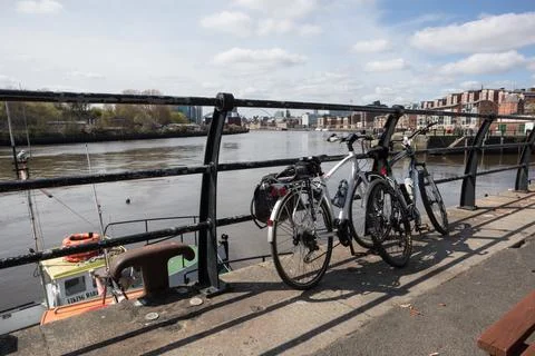Pair of mountain bikes leaning on railing by river in the sunshine Stock Photos