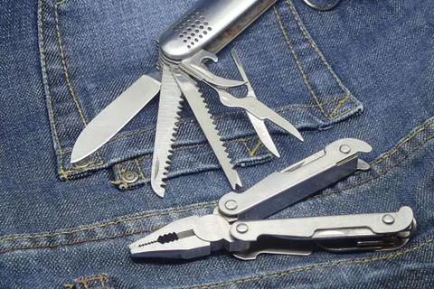 Pair multi kit hardware knife screwdriver metal tool close up on denim overal Stock Photos