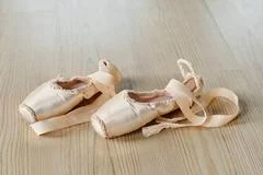 Slim legs of young ballet dancer in white tights and beige silk