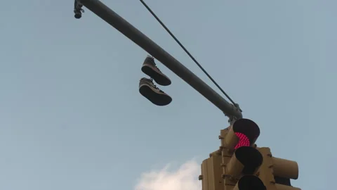 Pair of Nike shoes hanging on pole with traffic light 스톡 동영상 335306774