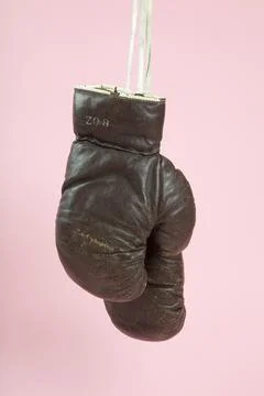A pair of old boxing gloves hung in front of a candy-pink background Stock Photos