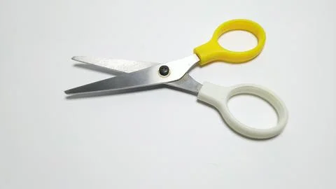 A pair of open scissors with yellow and white handles on a white background. Stock Photos
