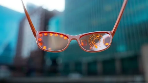 Pair of orange smart glasses laying on black desk. AR overlay showing functions. 스톡 동영상 202279454