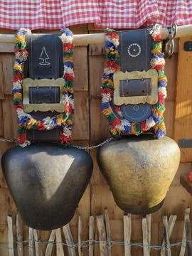 Pair of oversized rustic cowbells with bright woven straps hanging on weather Stock Photos