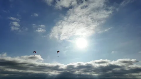 A Pair Of Paragliders Soaring Across A Sunny Blue Sky Background 4K Stock Footage 314778015