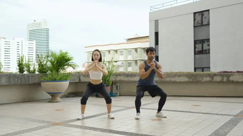 Pair Performing Squats on Rooftop 스톡 동영상 293427990