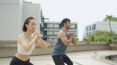 Pair Performing Squats on Rooftop Terrace for Strength Training Stock Footage 293427868