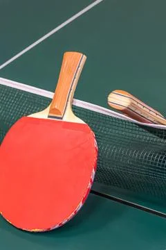 Pair of ping pong rackets set against a grid and green table Stock Photos