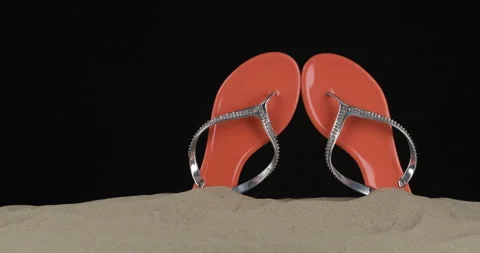 Pair of pink flip flops embellished with rhinestones stick out of the sand 스톡 동영상 170285711