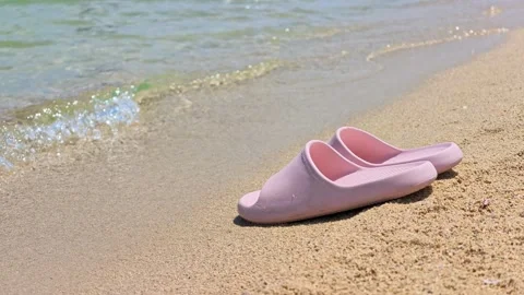 Pair of pink flip flops sits near tide line Stock Footage 341735002