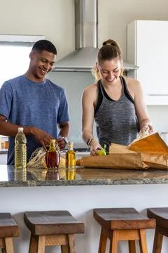 Pair placing brown bag on kitchen island, unpacking, cooking with animated Fotos Stock