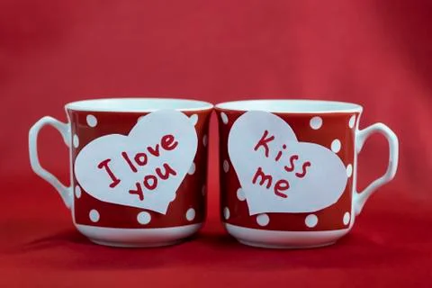 A pair of red cups in polka dots stand on the table. Two white hearts made of Stock Photos