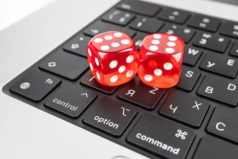 A pair of red dice rests on a computer keyboard, symbolizing chance, risk, .. Photos