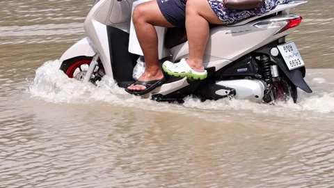 A pair rides a motorcycle through a flooded street Stock Footage 341481572