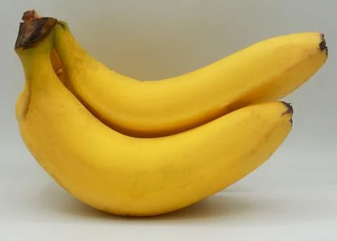 Pair of ripe bananas placed parallel to each other on a clean white background. Stock Photos