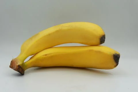Pair of ripe bananas placed parallel to each other on a clean white background. Stock Photos