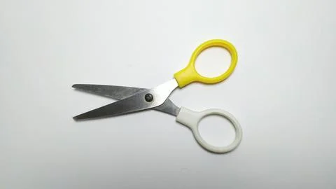 A pair of scissors with one yellow and one white handle on a white background Stock Photos