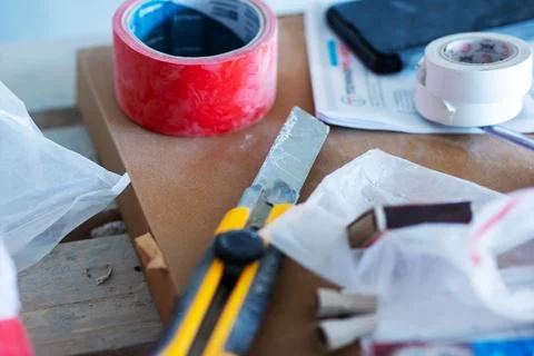 A pair of scissors is placed next to a roll of bright red tape Stock Photos