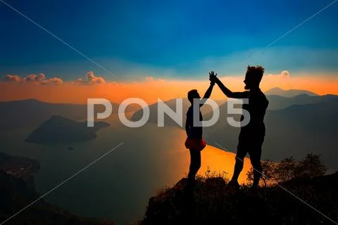 A pair shake hands in victory on top of a mountain Stock Photos