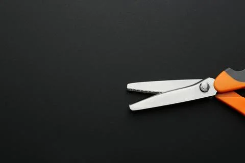 Pair of sharp scissors on dark background, top view. Space for text Stock Photos